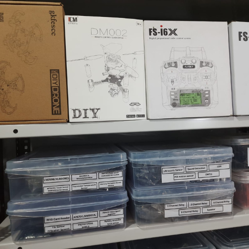 RoboSaki store shelf displaying boxes of drones and various electronic components neatly arranged.